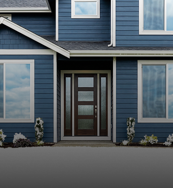 Modern home exterior featuring a blue siding facade, large windows, and a stylish wooden front door, emphasizing exterior maintenance and winter preparation.